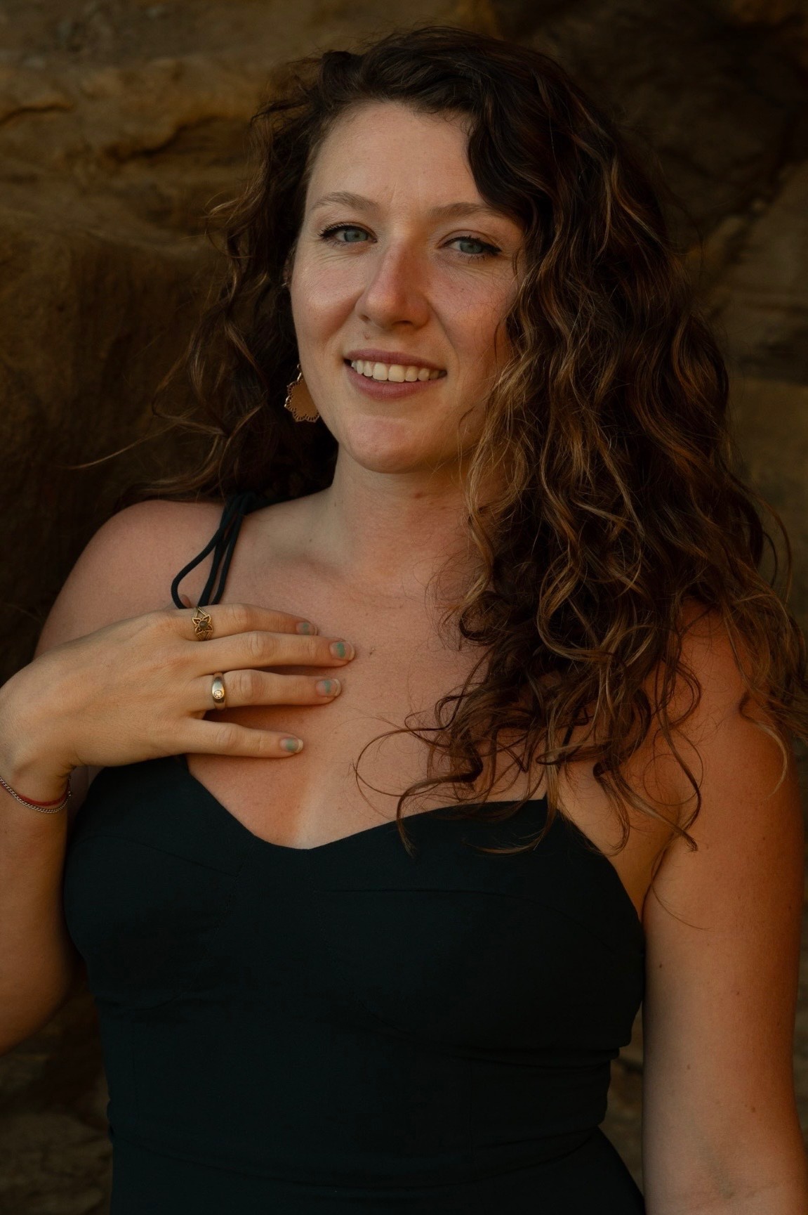 Christina Horn smiling in a black dress against warm sandstone